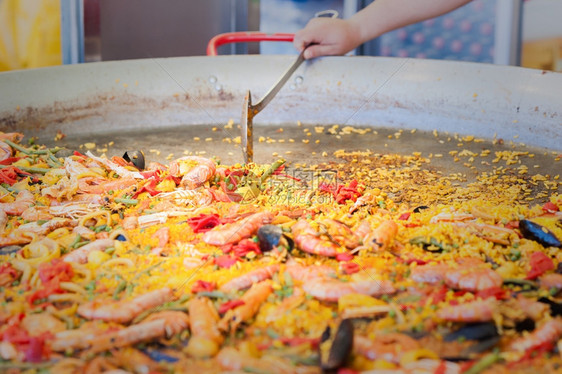 手在街头食品市场一个配有海鲜和鸡肉的西班牙传统辣椒饼配有海鲜和鸡烹饪传统的图片