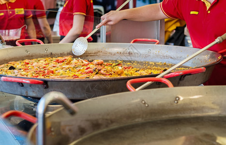 白饭盘子在街头食品市场一个配有海鲜和鸡肉的西班牙传统辣椒饼配有海鲜和鸡手图片