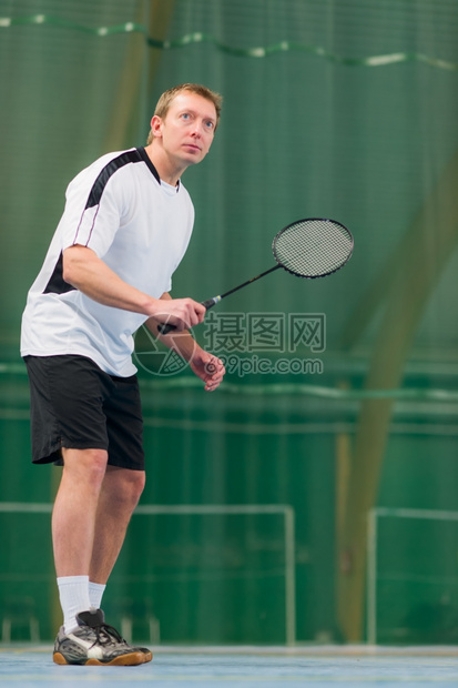 玩男人把注意力集中在羽毛球游戏上低角度播放器球拍图片