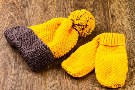 木材针线活黄色编织帽和木制背景的手套连指图片