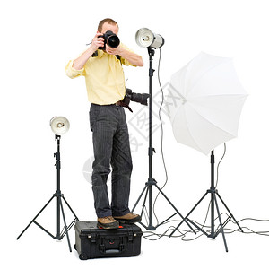 一名专业摄影师站在一个飞行箱子上在一个工作室里得到更高的角度周围有3个摄像头灯光单反拍照片图片