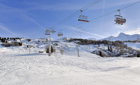 阿尔卑斯山采取寒冷的在高山度假胜地的坡上冬季运动滑雪员和在高山度假胜地的椅子拖车图片