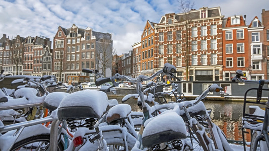 风景优美下雪的荷兰冬季在阿姆斯特丹的雪小自行车建筑的图片