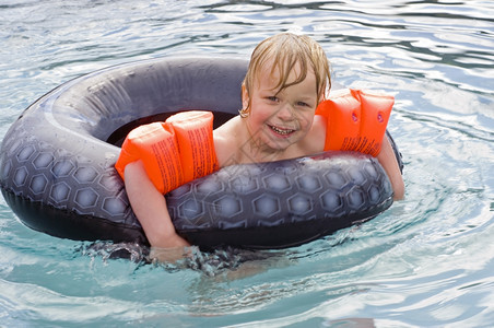 年轻男孩在户外游泳池玩得开心溅起湿的享受图片