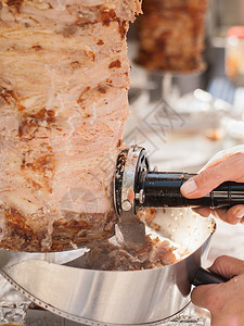 火鸡街道厨师用电刀割切烤肉串的手烤肉串是土耳其的典型菜盘美食图片