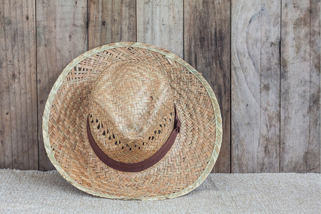 夏天棕色布料上的威克帽以木质背景为依附编织头饰图片