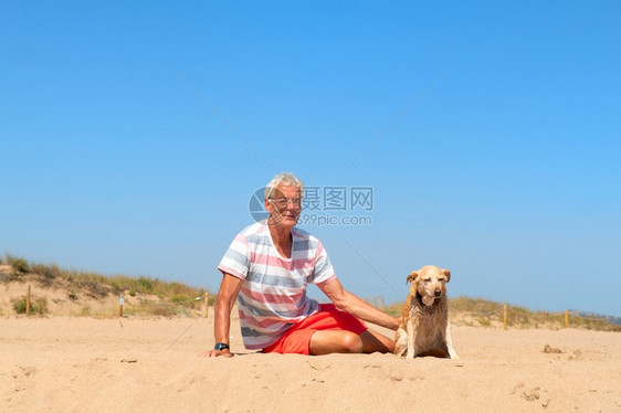 男子和老狗一起躺在沙滩上图片