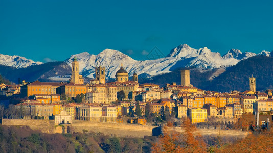 早晨旅行纪念碑Bergamo市在白山后面高雪下清晨的阳光图片