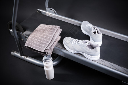 成套工具健身房带运动鞋和瓶水在黑色背景上运行的脚步图片