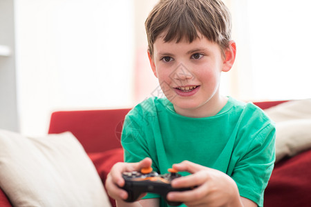 在家玩电脑游戏时坐在沙发上的男孩线游戏玩家人们图片