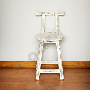面对平墙背景的石制白色木板凳的空椅子图片