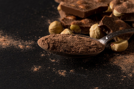 榛子黑色背景的勺中碎巧克力坚果片和可粉细节黑暗的图片