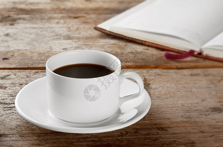 黑色的茶点气泡白圆杯黑咖啡在木桌和一本书背景图片