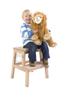 一种个3岁的男孩坐在凳子上拿着一只玩具狮子微笑着老的木头图片