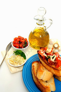 Bruschetta与橄榄油布鲁谢塔一起在绿石板上配有烤面包条片和更多番茄巴西尔大蒜和橄榄油包括一个小型白色容器中磨焦的亚洲奶酪图片