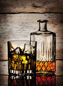 反射一种瓶装威士忌和一杯放在木头背景上图片