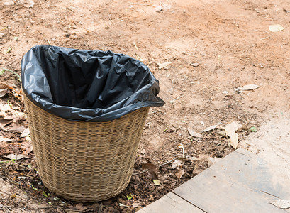 包木头正面Wicker篮子垃圾桶在农村住宅前的地面上图片