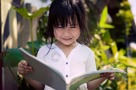 经验童年在家庭花园看书的年幼儿童读图片