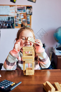 游戏家小女孩学龄前幼童玩木砖具建造一座塔构筑房子的概念快乐图片