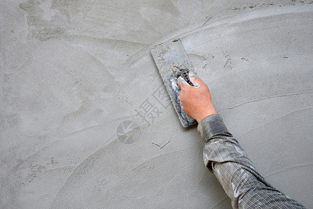 泥水匠成人具体的在建筑工地混凝土墙背景的水泥石膏上用粗金刚石打板的人手图片