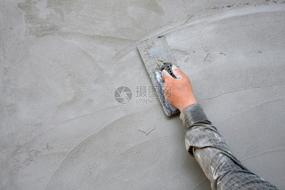 泥水匠成人具体的在建筑工地混凝土墙背景的水泥石膏上用粗金刚石打板的人手图片