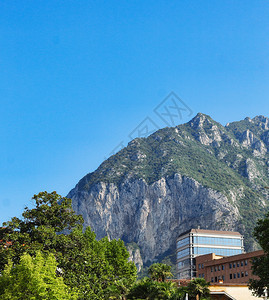 风景旅游行地貌观在岩石山附近建筑房屋和蓝天下山丘上的绿林图片