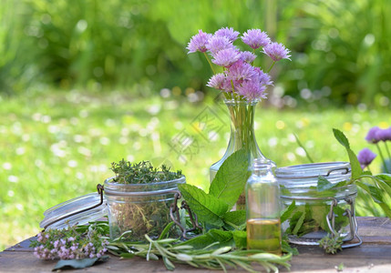 薄荷新鲜的将玻璃罐和油瓶装在花园的一张桌子上安排的瓶中玻璃罐和油药物图片