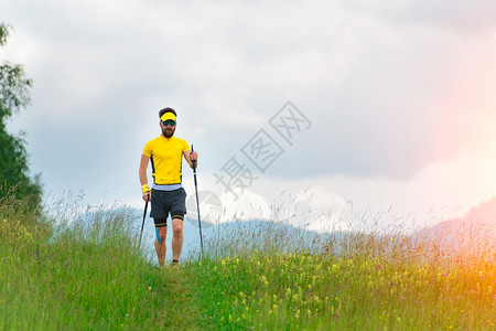 北欧在一名年轻男子运动员的山草地上行走耐力男人训练图片