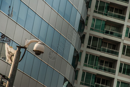 警卫私人的城市背景墙上现代监控摄像头已经发展的监视和目检查概念已开发的市景背墙上现代监控摄像机数字的图片