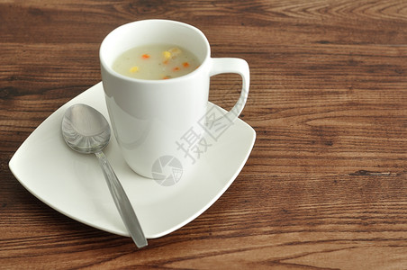 一杯蔬菜汤用勺子和盘在木制背景上展示桌子晚餐可口图片