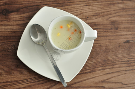 热的新鲜一杯蔬菜汤用勺子和盘在木制背景上展示健康图片