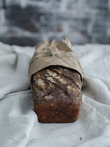 包装在克拉夫纸上的自制黑麦面包裹木制的早餐图片