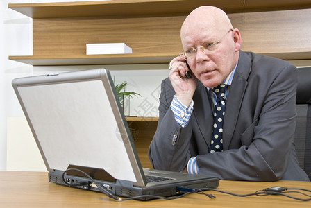 商业老板正面一名公司经理坐在笔记本电脑前在移动话上说a一名公司经理图片