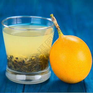 由甜西番莲或制成的新鲜果汁其种子在玻璃杯中西番莲果在侧面选择聚焦在玻璃的前缘和西番莲面喝它茶点图片