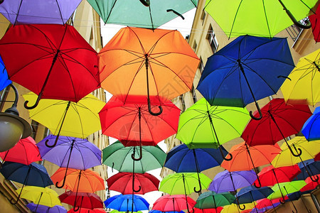 丰富多彩的保护悬挂在顶层各不同伞的一组顶部彩色雨伞挂在顶层地方标志上的彩色雨伞颜图片