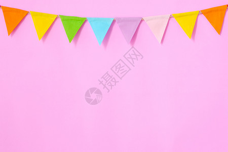 三角形节日挂在粉红背景生日周年纪念庆祝活动贺卡背景的彩色政帜贴在花上粉色的图片