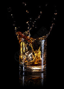 威士忌从冰块上喷出玻璃杯中的冰块里流出威士忌以黑色底的威士忌碎片从玻璃里的冰块分离出来苏格兰人酒精饮料图片