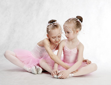 芭蕾舞短裙垂直的两个小女孩芭蕾舞女坐在地上的塔图高图片
