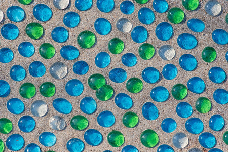装饰风格马赛克在沙滩上为背景排列的日光白蓝色和绿玻璃珠的景观图象圆形的图片