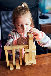 快乐的游戏小女孩学龄前幼童玩木砖具建造一座塔构筑房子的概念教育图片