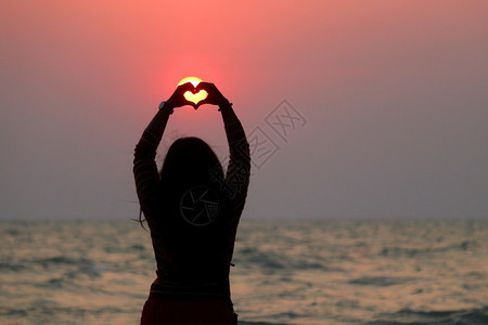 海滩雌手的轮光在阳下造心形状闲暇图片