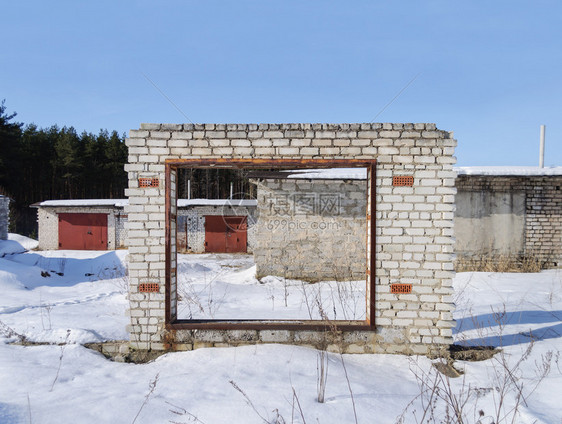 郊区俄罗斯雪查看车库线在阳光寒冬日前方被摧毁的白砖车库大门图片