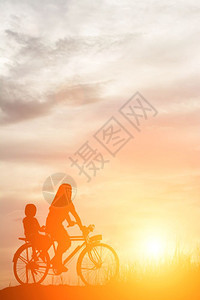 爱母亲和女儿在日落快乐时光骑自行车的休眠水人们图片