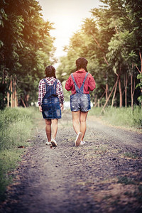 太阳两个女孩在森林道路上行走保持年轻的图片