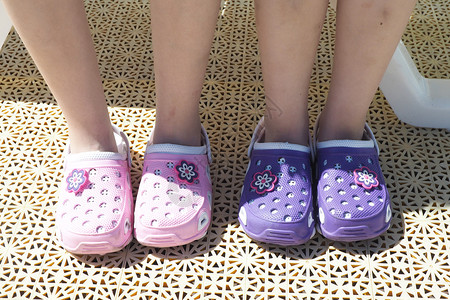 木板粉色的两对孩子双脚用明亮紫色和粉红海滩橡皮拖鞋姐妹图片