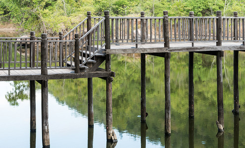 池塘小湖上通往寺庙的老木桥户外图片