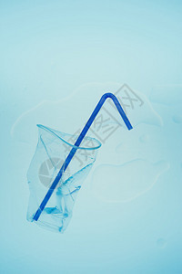 概念的环境节省蓝色背景上压扁的塑料杯和吸管收集塑料垃圾以回收污染和过多垃圾的概念顶部复制空间图片