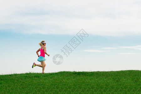 快速地户外女子运动员穿着彩色服装在草地上跑竞技图片