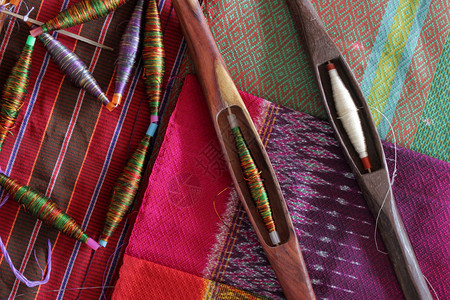 颜色缝传统编织泰国丝绸的质织物上花彩波本和木制bobbin生的图片