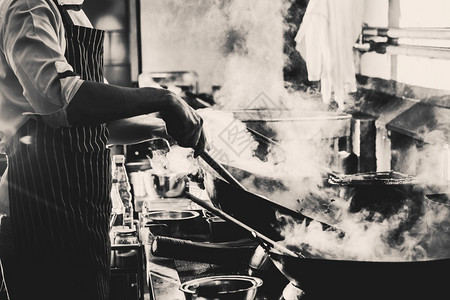 热的搅拌厨房黑白过滤器和厨房的火力猛烈地烧烤在wokDramatic烹饪中做厨师煎锅专业的图片
